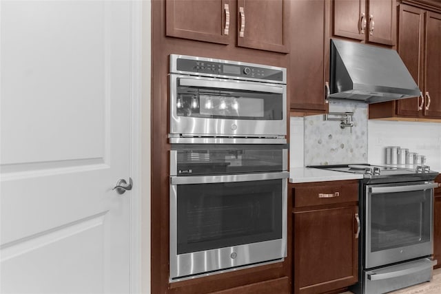 11597 Weaver Hollow Rd, New Port Richey, FL 34654 - kitchen featuring appliances with stainless steel finishes, exhaust hood, tasteful backsplash, and light countertops