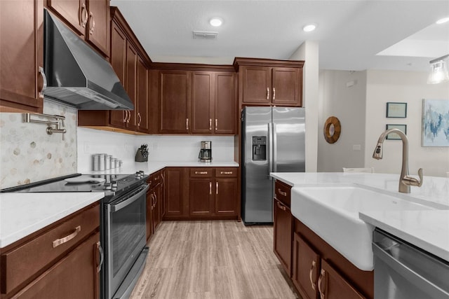 11597 Weaver Hollow Rd, New Port Richey, FL 34654 - kitchen featuring appliances with stainless steel finishes, under cabinet range hood, light countertops, and light wood finished floors