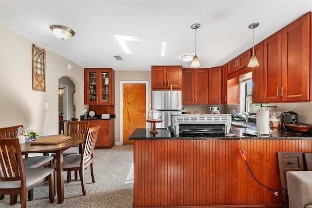 3622 W Mullen Ave, Tampa, FL 33609 - kitchen featuring a peninsula, freestanding refrigerator, arched walkways, glass insert cabinets, and pendant lighting