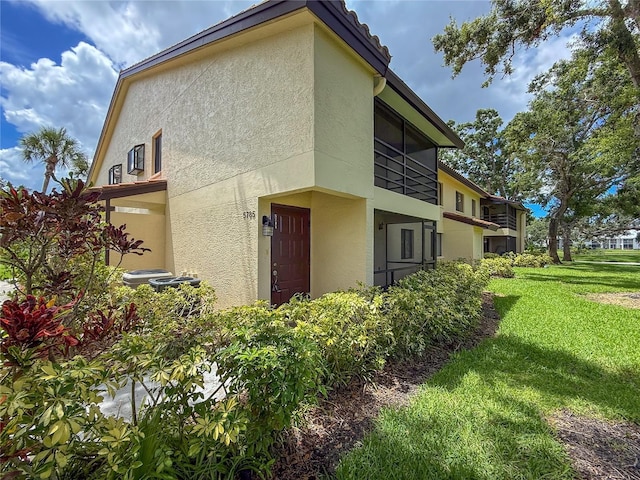 5785 Gardens Dr, Sarasota, FL 34243 - view of side of home featuring stucco siding and a lawn