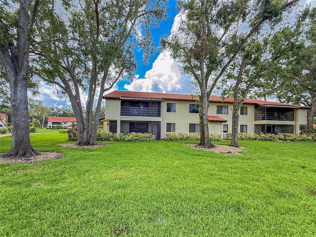 5785 Gardens Dr, Sarasota, FL 34243 - back of house with stucco siding, a balcony, a yard, and a tiled roof
