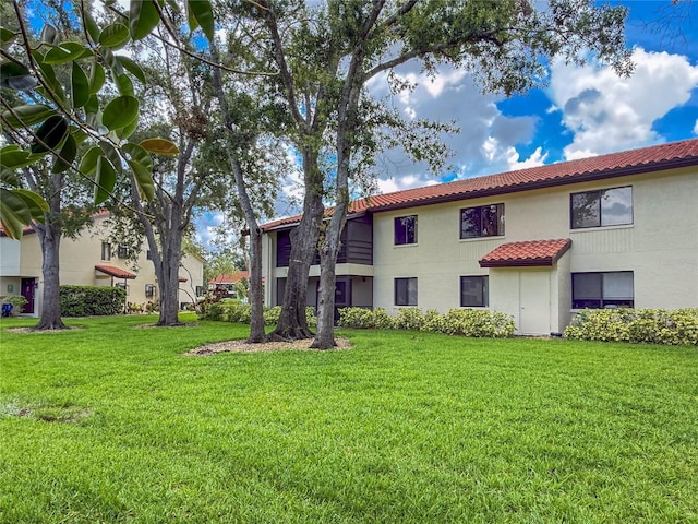 5785 Gardens Dr, Sarasota, FL 34243 - back of property with a tile roof, a yard, and stucco siding