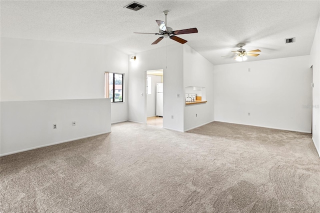 5785 Gardens Dr, Sarasota, FL 34243 - unfurnished living room featuring vaulted ceiling, ceiling fan, carpet flooring, and a textured ceiling