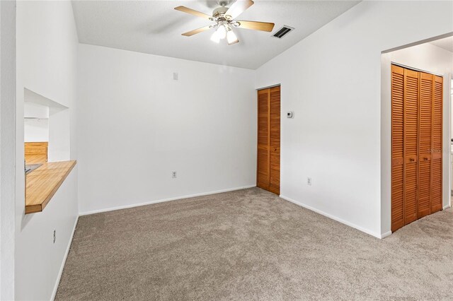 5785 Gardens Dr, Sarasota, FL 34243 - unfurnished bedroom with multiple closets, carpet, lofted ceiling, and ceiling fan