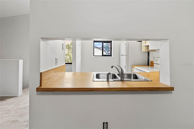 5785 Gardens Dr, Sarasota, FL 34243 - kitchen featuring white appliances, carpet flooring, and a peninsula