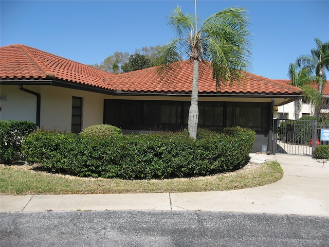 5785 Gardens Dr, Sarasota, FL 34243 - view of side of property featuring a tile roof, stucco siding, and a gate