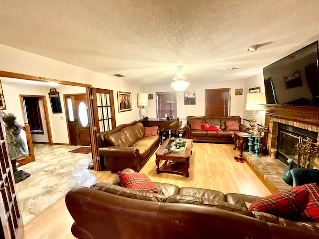 8834 Whispering Oaks Trl, New Port Richey, FL 34654 - living area featuring a chandelier, a brick fireplace, a textured ceiling, and wood finished floors