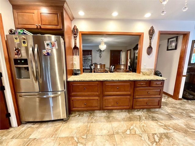 8834 Whispering Oaks Trl, New Port Richey, FL 34654 - kitchen featuring stainless steel fridge with ice dispenser, a chandelier, brown cabinetry, and light stone countertops