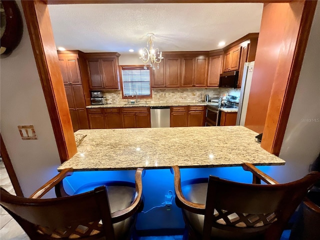 8834 Whispering Oaks Trl, New Port Richey, FL 34654 - kitchen featuring appliances with stainless steel finishes, a chandelier, backsplash, a breakfast bar, and brown cabinetry