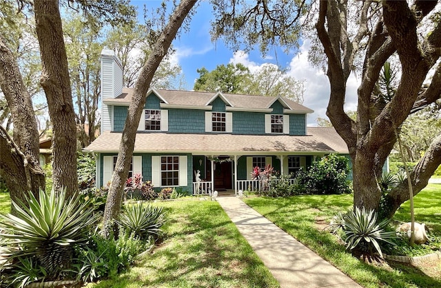 8834 Whispering Oaks Trl, New Port Richey, FL 34654 - view of front of house with a chimney, a porch, a front lawn, and roof with shingles