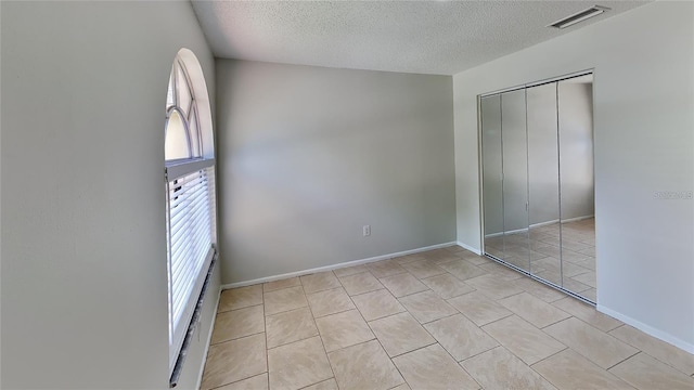 1421 Mohrlake Dr, Brandon, FL 33511 - unfurnished bedroom with multiple windows, a textured ceiling, a closet, and light tile patterned flooring