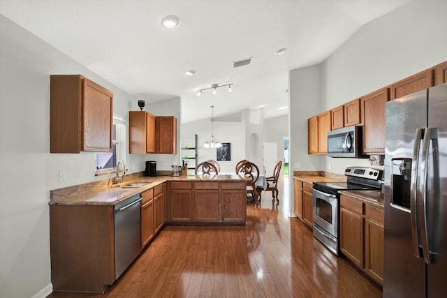 18419 Merseyside Loop, Land O Lakes, FL 34638 - kitchen with stainless steel appliances, vaulted ceiling, dark wood-type flooring, a peninsula, and brown cabinets