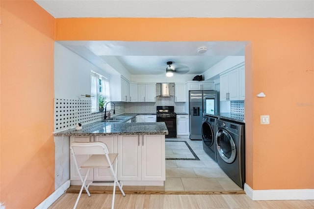 12995 NE 5th Ave, North Miami, FL 33161 - kitchen featuring washing machine and dryer, black range, stainless steel fridge, a peninsula, and dark stone counters