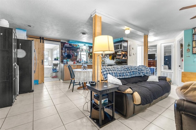 7441 Cypress Dr, New Port Richey, FL 34653 - living area with light tile patterned floors, a barn door, ceiling fan, and a textured ceiling