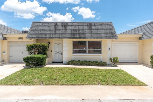 7000 Lafayette N, Pinellas Park, FL 33781 - view of front facade with an attached garage, concrete driveway, stucco siding, and mansard roof