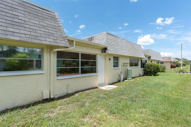 7000 Lafayette N, Pinellas Park, FL 33781 - view of property exterior featuring mansard roof, stucco siding, a lawn, and roof with shingles