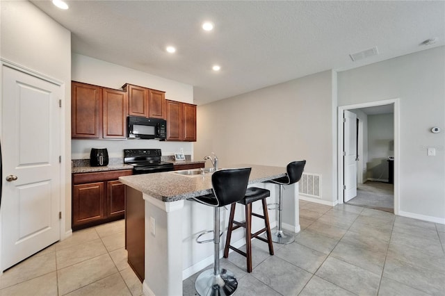 10119 Rose Petal Pl, Riverview, FL 33578 - kitchen featuring black appliances, a kitchen breakfast bar, an island with sink, recessed lighting, and light tile patterned flooring
