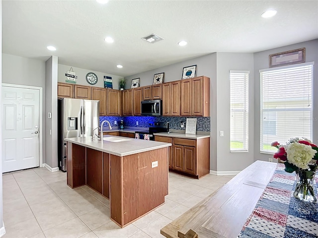 5830 100th Ave E, Parrish, FL 34219 - kitchen with stainless steel appliances, light countertops, light tile patterned floors, decorative backsplash, and a kitchen island with sink