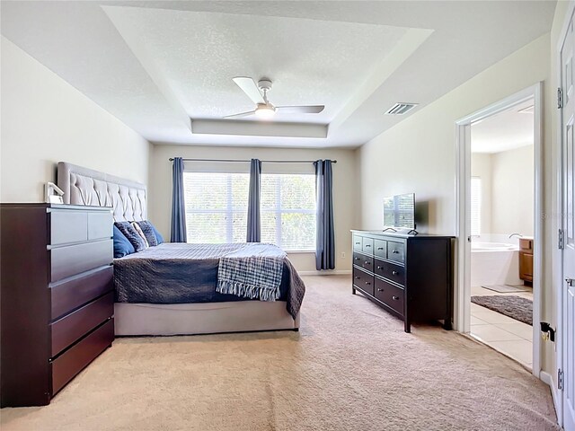 5830 100th Ave E, Parrish, FL 34219 - bedroom with light colored carpet, a tray ceiling, multiple windows, and connected bathroom