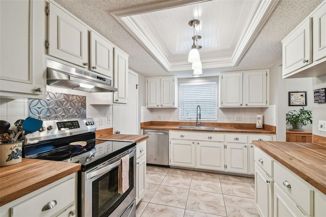 4108 Woodtrail Blvd, New Port Richey, FL 34653 - kitchen with wooden counters, appliances with stainless steel finishes, under cabinet range hood, white cabinetry, and crown molding