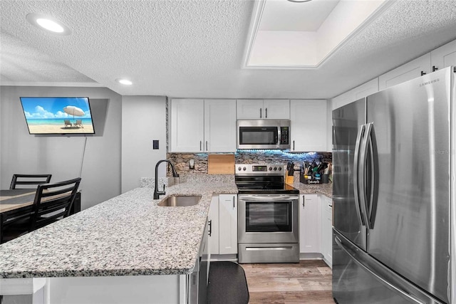 3350 Fox Hunt Dr, Palm Harbor, FL 34683 - kitchen with appliances with stainless steel finishes, a peninsula, a textured ceiling, white cabinets, and recessed lighting
