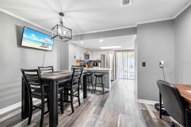 3350 Fox Hunt Dr, Palm Harbor, FL 34683 - dining space featuring a textured ceiling, wood finished floors, crown molding, a chandelier, and recessed lighting