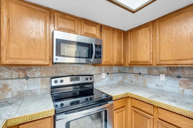 7811 Niagara Ave Unit 2125, Tampa, FL 33617 - kitchen with appliances with stainless steel finishes, backsplash, tile countertops, and brown cabinetry
