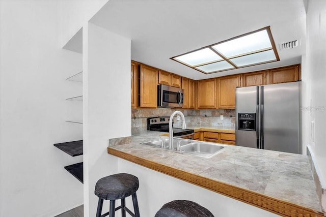 7811 Niagara Ave Unit 2125, Tampa, FL 33617 - kitchen with appliances with stainless steel finishes, brown cabinets, tasteful backsplash, a breakfast bar, and tile counters