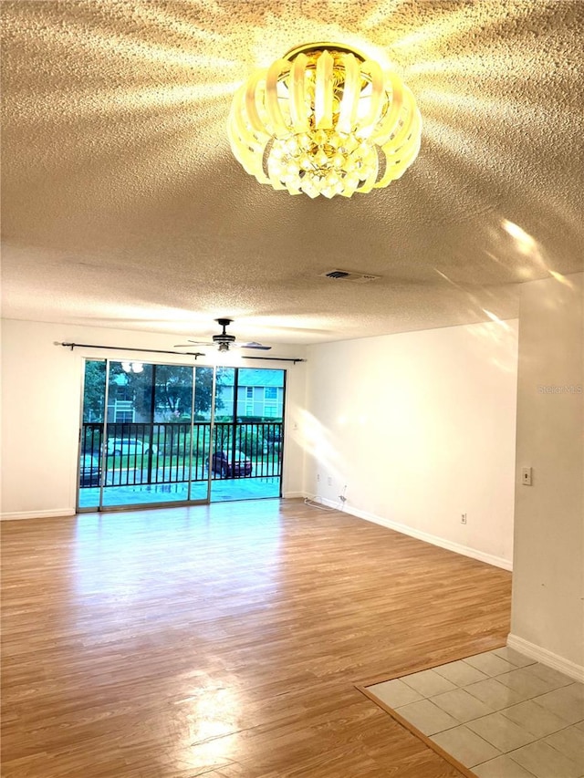 4207 Winding Moss Trl Unit 201, Tampa, FL 33613 - spare room with wood finished floors, a chandelier, ceiling fan, and a textured ceiling