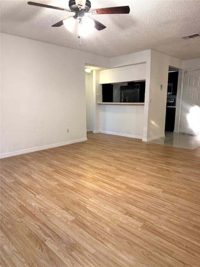 4207 Winding Moss Trl Unit 201, Tampa, FL 33613 - unfurnished living room featuring a textured ceiling, light wood-style flooring, and a ceiling fan