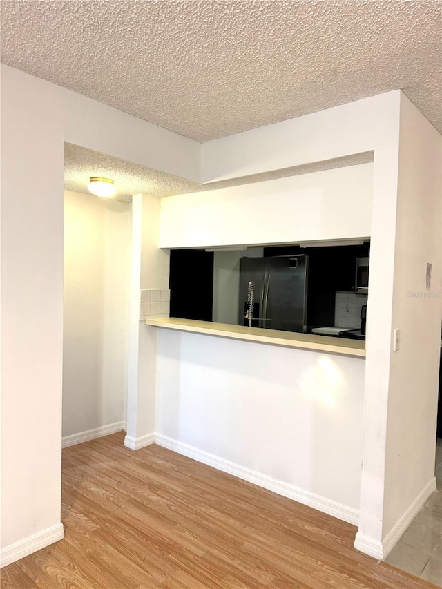4207 Winding Moss Trl Unit 201, Tampa, FL 33613 - kitchen with black refrigerator with ice dispenser, wood finished floors, stainless steel microwave, and a textured ceiling