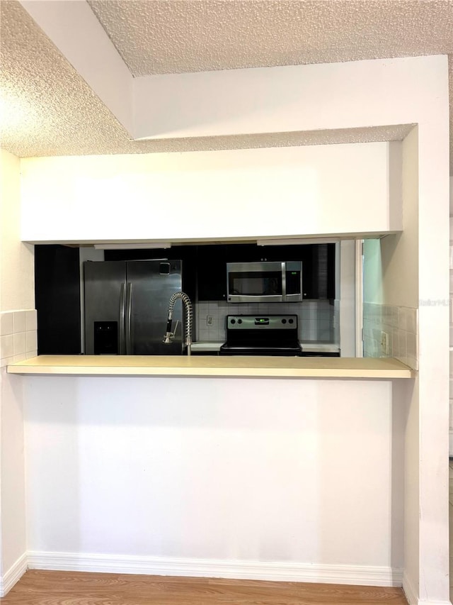 4207 Winding Moss Trl Unit 201, Tampa, FL 33613 - kitchen featuring fridge with ice dispenser, stainless steel microwave, black electric range oven, a textured ceiling, and wood finished floors