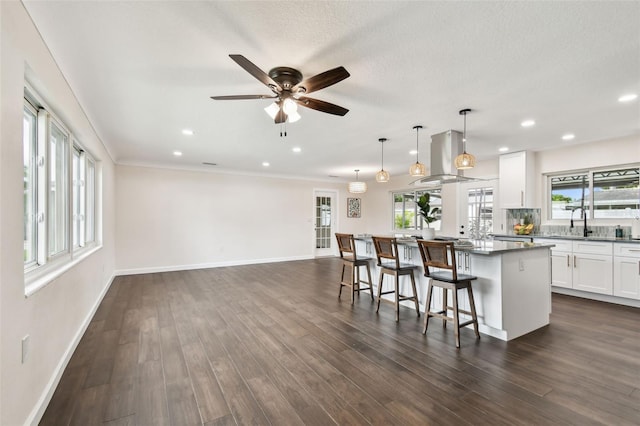 5934 51st Ave N, Kenneth City, FL 33709 - kitchen with island exhaust hood, a kitchen island, ceiling fan, a kitchen breakfast bar, and white cabinets