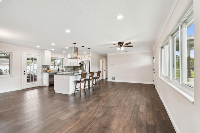 5934 51st Ave N, Kenneth City, FL 33709 - kitchen with a kitchen breakfast bar, open floor plan, a center island, white cabinets, and dark wood-type flooring