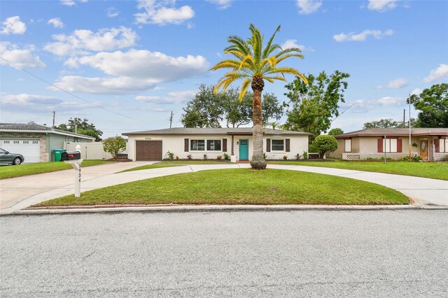 5934 51st Ave N, Kenneth City, FL 33709 - view of front of house with curved driveway, a garage, a front lawn, and stucco siding