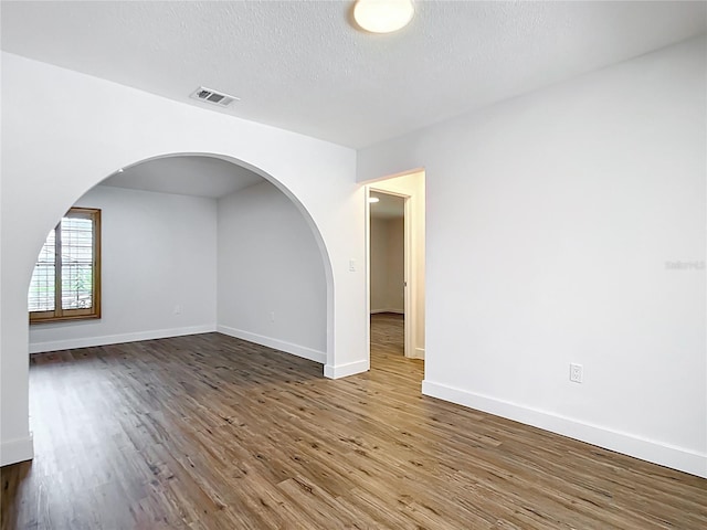 20352 Astoria Ave, Port Charlotte, FL 33952 - spare room with wood finished floors, a textured ceiling, and arched walkways