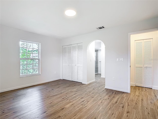 20352 Astoria Ave, Port Charlotte, FL 33952 - unfurnished bedroom featuring arched walkways, a closet, and wood finished floors