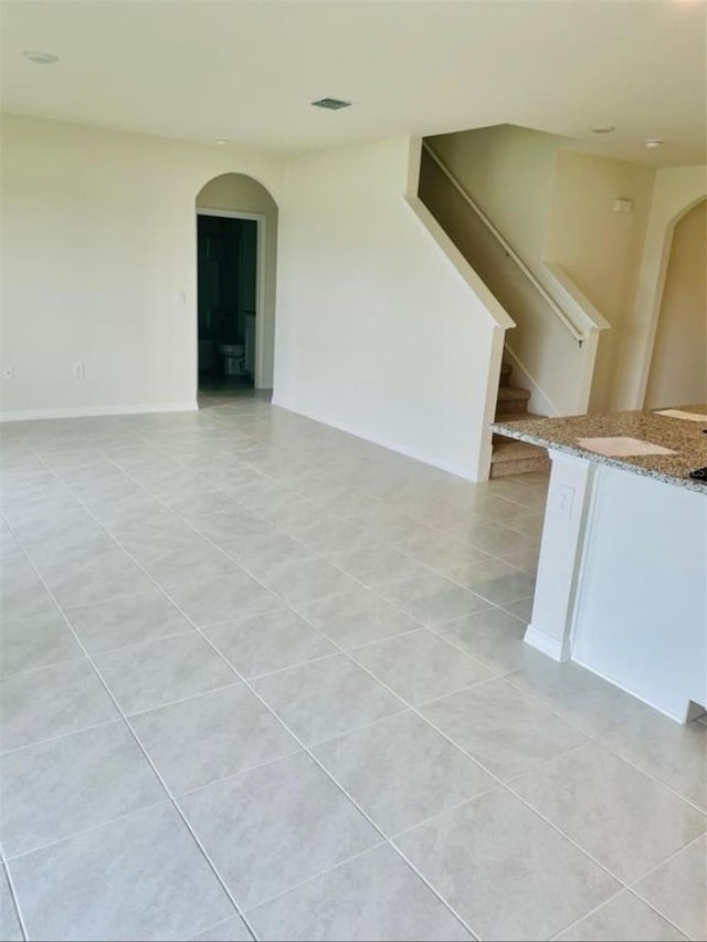5543 Siltstone St, Lakeland, FL 33811 - spare room featuring arched walkways, light tile patterned flooring, and stairway