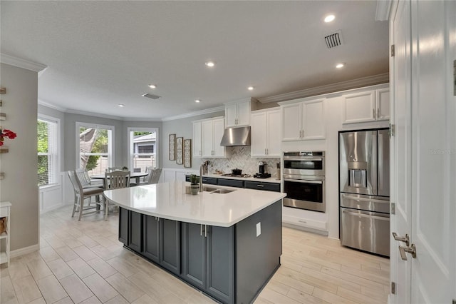 10399 Boyette Brook St, Riverview, FL 33569 - kitchen featuring appliances with stainless steel finishes, crown molding, white cabinetry, under cabinet range hood, and light countertops