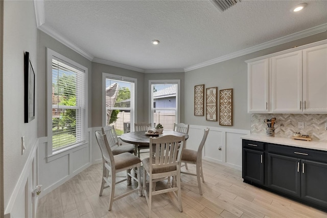 10399 Boyette Brook St, Riverview, FL 33569 - dining space featuring a decorative wall, a wainscoted wall, a textured ceiling, light wood finished floors, and crown molding