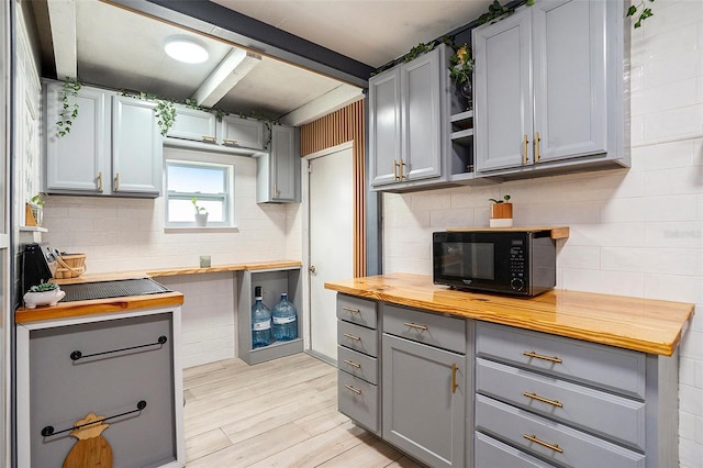 15906 Country Farm Pl, Tampa, FL 33624 - kitchen with black microwave, gray cabinets, butcher block countertops, and backsplash