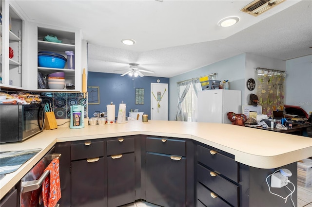 7018 Arbor View Ln, New Port Richey, FL 34653 - kitchen with black microwave, light countertops, a peninsula, a ceiling fan, and a textured ceiling