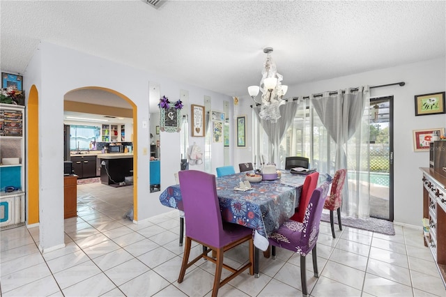 7018 Arbor View Ln, New Port Richey, FL 34653 - dining room featuring a textured ceiling, a chandelier, arched walkways, and light tile patterned floors