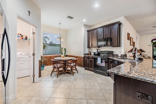 12251 Duckett Ct, Spring Hill, FL 34610 - kitchen featuring black appliances, washer / clothes dryer, dark stone counters, dark brown cabinetry, and light tile patterned flooring