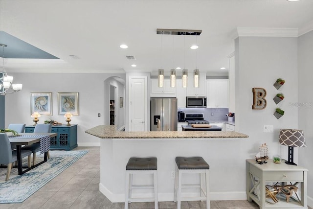 10450 Highland Park Pl, Palmetto, FL 34221 - kitchen featuring stainless steel appliances, a peninsula, crown molding, arched walkways, and a kitchen breakfast bar
