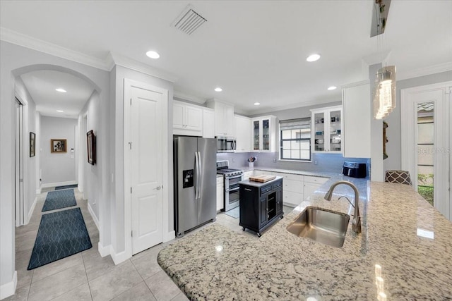 10450 Highland Park Pl, Palmetto, FL 34221 - kitchen with stainless steel appliances, crown molding, arched walkways, light stone counters, and white cabinetry