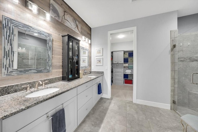 10450 Highland Park Pl, Palmetto, FL 34221 - bathroom featuring a stall shower, double vanity, wooden walls, tile patterned floors, and a spacious closet