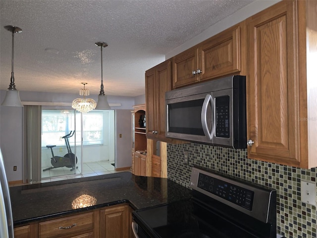 3123 29th Ave N Unit 105, Saint Petersburg, FL 33713 - kitchen featuring appliances with stainless steel finishes, decorative backsplash, a chandelier, brown cabinets, and a textured ceiling