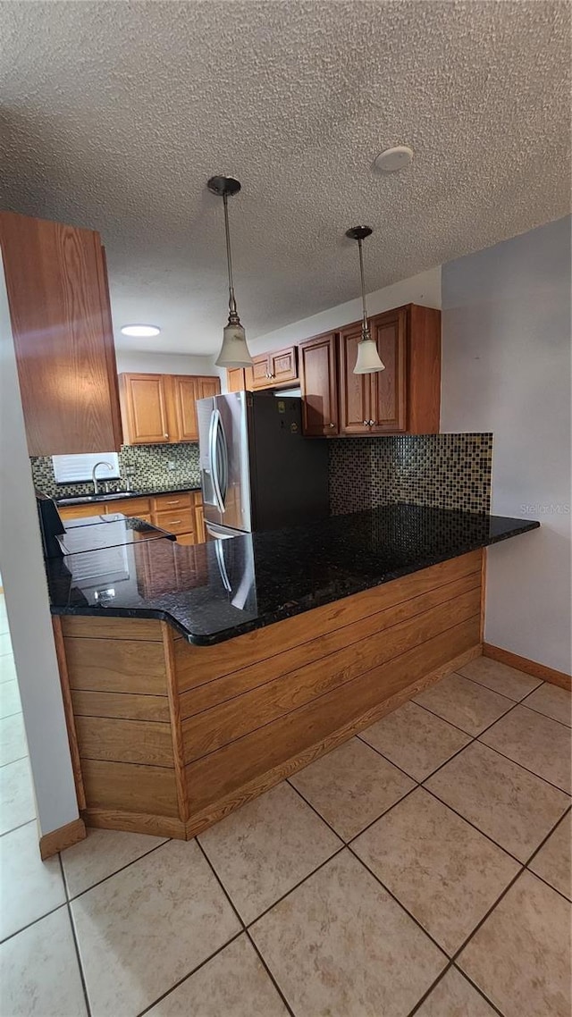 3123 29th Ave N Unit 105, Saint Petersburg, FL 33713 - kitchen featuring stainless steel fridge with ice dispenser, tasteful backsplash, a peninsula, brown cabinets, and a textured ceiling