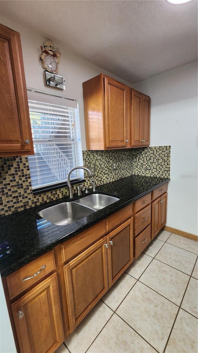 3123 29th Ave N Unit 105, Saint Petersburg, FL 33713 - kitchen featuring decorative backsplash, brown cabinetry, a textured ceiling, light tile patterned flooring, and dark stone counters